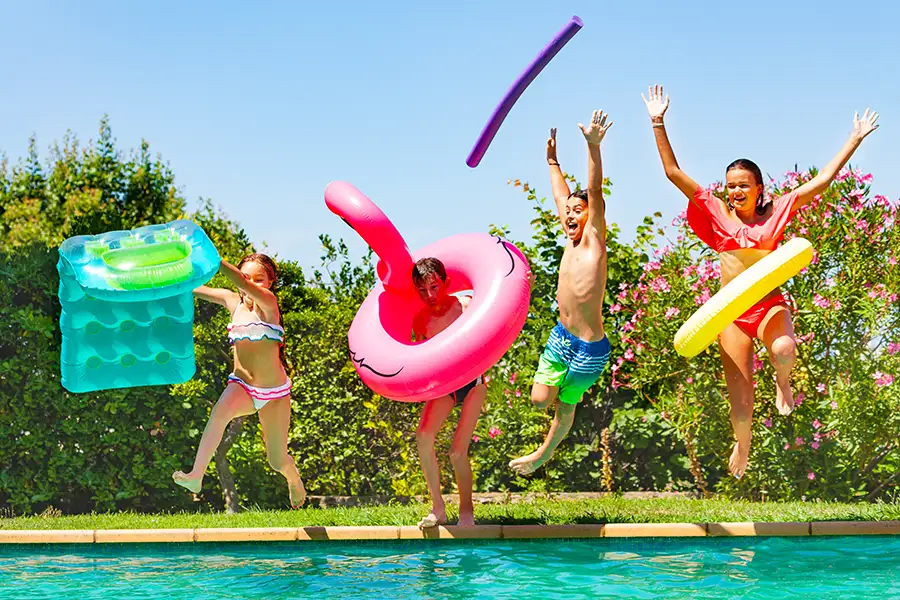 group of kids, friends enjoying inflatable pool toys and floats, jumping into pool - Decatur, IL